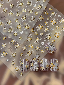Détail de stickers à ongles fleurs dorées et motifs de nœuds blancs sur ongles