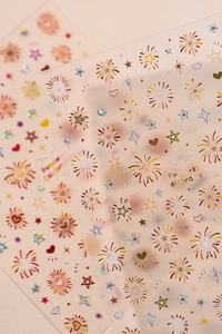 Macro detail of holographic firework, star, and heart nail art stickers with metallic finish