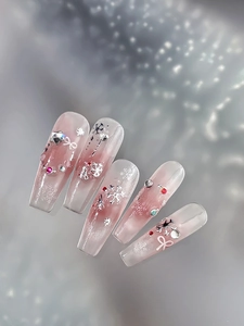 Detail of pink gradient press-on nails with silver snowflakes, bows and sparkling rhinestones