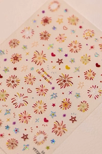 Detail shot of laser fireworks and star nail stickers on a beige textured background
