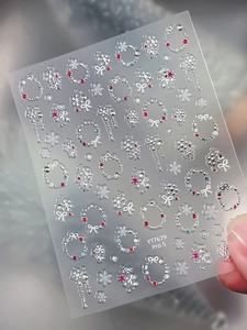 Macro shot of embossed silver snowflake nail stickers with festive winter wreath patterns