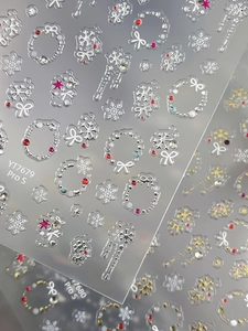 Close-up of 3D embossed silver snowflake nail stickers with festive bow and candy cane details
