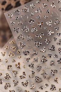Detailed close-up of heart leopard print nail stickers with metallic gold foil borders
