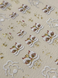 Dettaglio macro di adesivi 3D per unghie con disegni della danza del leone e nuvole d'oro