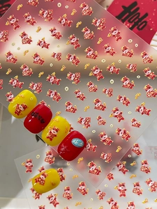 Vue détaillée des autocollants d'ongles dragon rouge sur des faux ongles rouges et jaunes