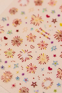 Close-up of colorful fireworks and laser star nail stickers with shiny heart patterns