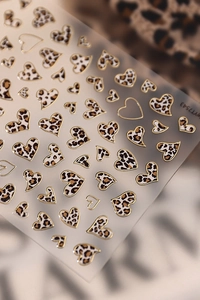 Macro detail of gold-trimmed leopard heart nail stickers on translucent backing LEY7543