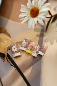 Détails de stickers à ongles fleurs marguerites avec French tips sur base rose clair