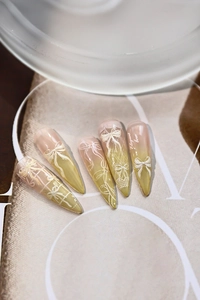 Macro view of long stiletto press-on nails with 3D embossed bows and lace textures