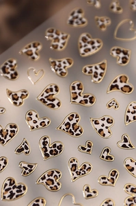 Macro shot of leopard print heart nail stickers with metallic gold embossed borders