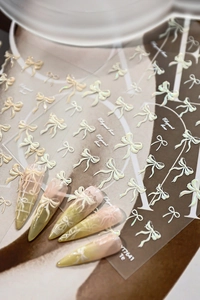 Macro shot of 3D shell bow nail stickers showing elegant pearl white relief details