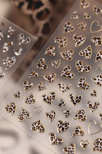 Detailed view of heart-shaped leopard print nail stickers with elegant gold foil borders