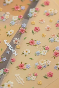 Vue macro de stickers 3D pour ongles avec de petites fleurs colorées et motifs de lettres