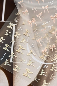 Macro view of 3D embossed bow nail stickers with iridescent pearl finish and elegant textures