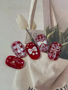 Detailed close-up of winter nail art stickers with red relief bows and pearl chains