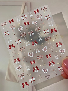 Macro detail of 5D embossed bow and star nail art stickers in red, white and gold