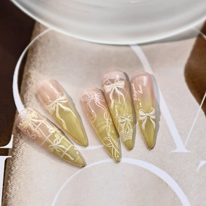 Elegant stiletto press-on nails with bow design, lace patterns, and lime green gradient