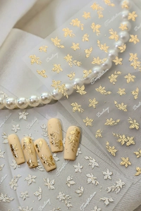 Detail of 3D gold flower nail stickers on matte nails with elegant pearl accessories