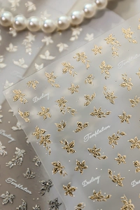 Macro shot of 3D embossed floral nail art stickers with metallic gold and silver finish