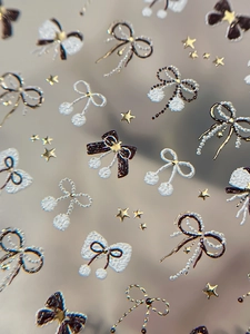 Close-up of 3D embossed nail stickers featuring gold bows, stars and pearl patterns