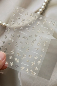 Macro shot of 5D embossed silver butterfly and floral nail decals with gold accents