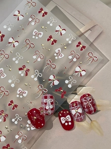 Detail of winter red and white bow nail stickers with 3D pearl texture and gold stars