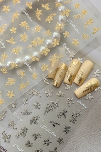 Close-up of gold and silver floral nail embossed stickers on soft pink nail tips