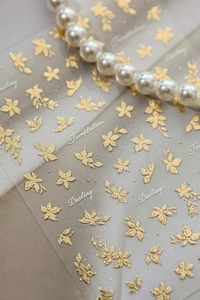 Detail of 3D embossed gold floral nail stickers with floral patterns and letter accents
