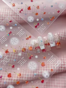Macro detail of 3D cherry and snowflake nail stickers with elegant cursive typography