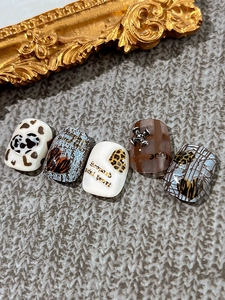 Detail of leopard print heart press-on nails with vintage 3D cross and love charms