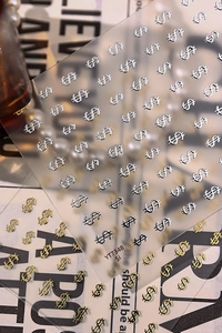 Close-up of gold and silver dollar sign nail art stickers with 3D embossed metallic finish