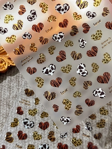 Macro shot of 3D embossed heart nail stickers with gold leopard and zebra prints