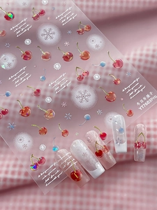 Detailed view of winter cherry and snowflake nail stickers on almond-shaped nails