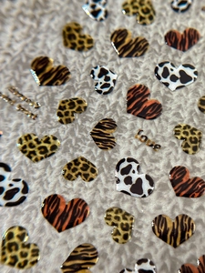 Detailed macro view of heart nail stickers featuring leopard and tiger animal patterns