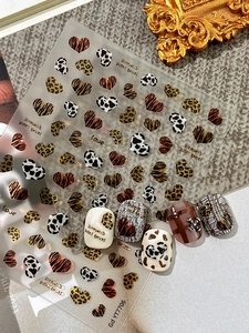 Close-up of leopard heart nail stickers with metallic stars and textured animal patterns