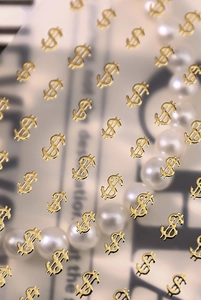 Detailed macro view of golden dollar sign nail art stickers with metallic texture finish