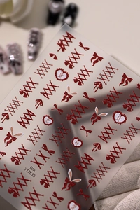 Macro shot of red glitter nail stickers featuring bowknot and heart pattern details