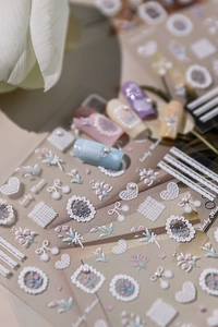 Macro shot of 3D embossed nail stickers featuring white tulips and pearl decorations