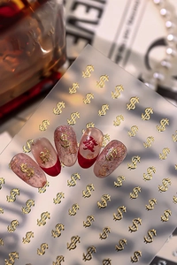 Detail of gold dollar sign nail stickers on red and pink nails with elegant background
