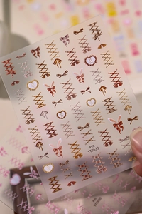 Detail of sweet ballerina bow and corset style nail stickers in brown and beige tones