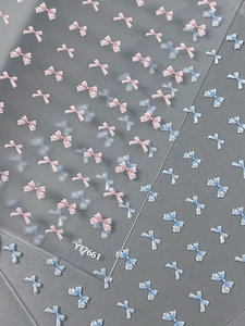 Macro view of 3D embossed pink and blue bow nail stickers with matte finish texture