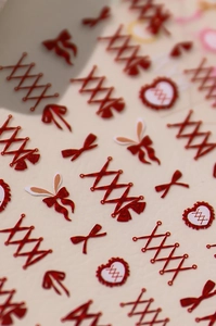 Macro shot of glitter red bow and ribbon nail art stickers with sweet heart designs
