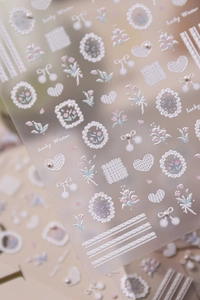 Macro detail of 5D embossed nail stickers featuring floral, heart, and pearl accents