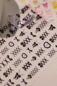 Macro detail of ballet-style nail stickers featuring brown lace ribbons and heart patterns