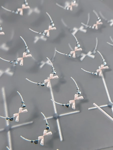 Macro shot of 5D embossed bow nail stickers with pink glitter and metallic beads