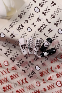 Detail view of gothic style nail stickers with bows and heart patterns on manicured tips