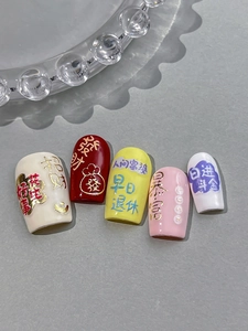 Detail of red and yellow nail charms with Chinese prosperity characters and gold patterns