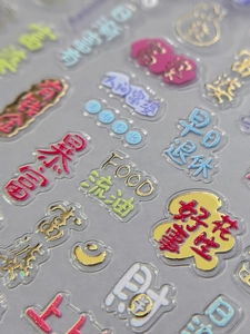 Macro shot of 3D epoxy nail stickers with gold accents and Chinese fortune text