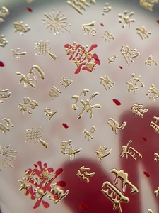 Vue macro de stickers d'ongles 3D en relief doré avec caractères chinois et rouge