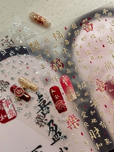 Détail de stickers à ongles 3D avec caractères festifs dorés et rouges du Nouvel An